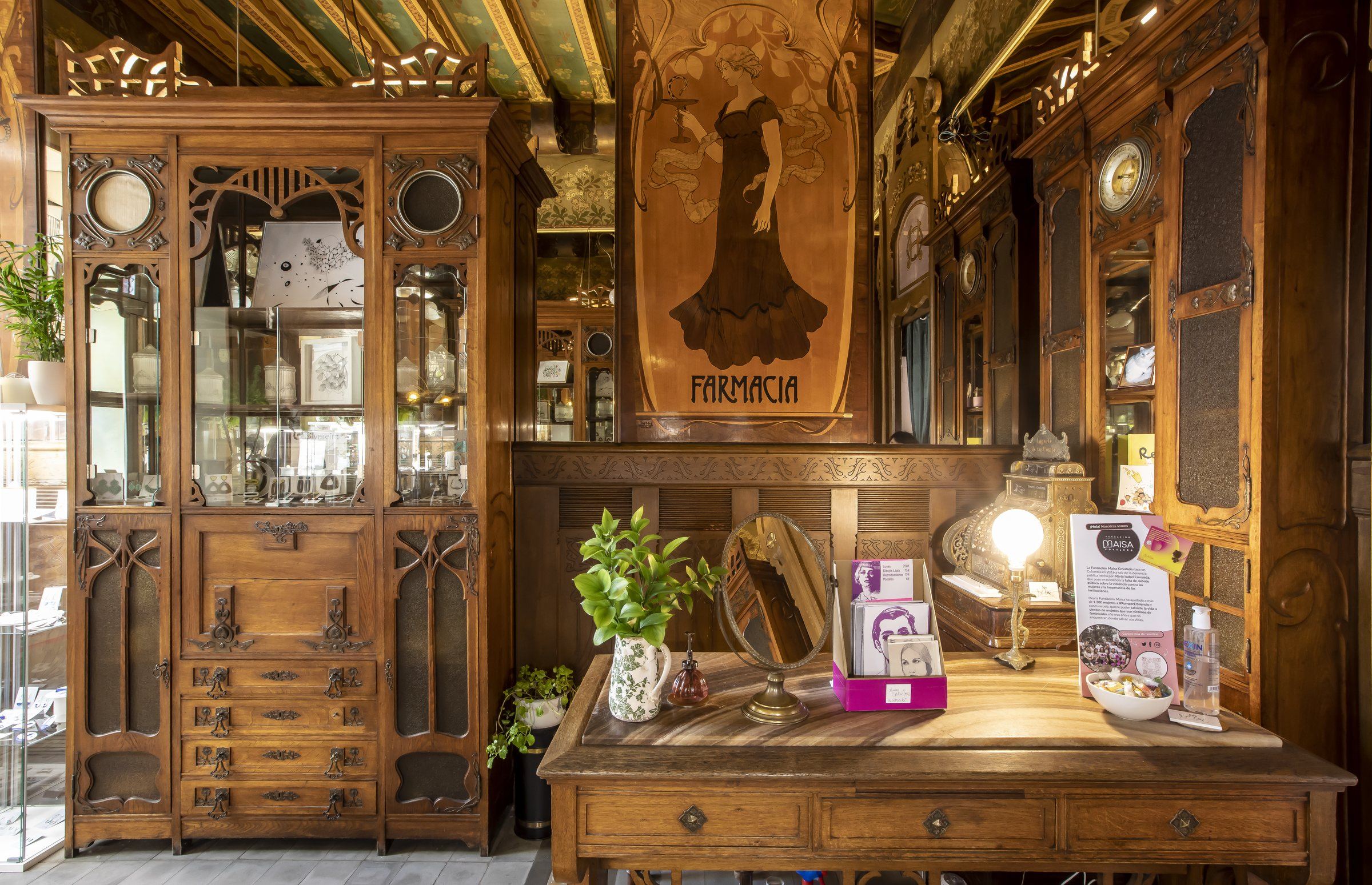 Mostrador y vitrina de madera de la antigua farmacia, con el rótulo original, flores y piezas de Lamai